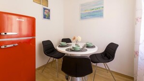 A compact room with a round dining table, four black chairs, a red refrigerator, and two wall-mounted air vents. - Apartment Rudolfspark Check in 15h to 22h Only (Vienna)