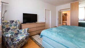A bedroom with a bed, a television on a dresser, a chair, and a walk-in closet. - Apartment Rudolfspark Check in 15h to 22h Only (Vienna)
