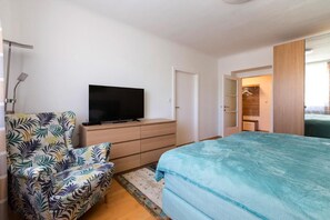 Una camera da letto con un letto, una televisione su una cassettiera, una sedia e un armadio a muro.
