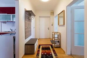 Een hal met een houten bankje, een tapijt met patroon en een spiegel aan de muur.