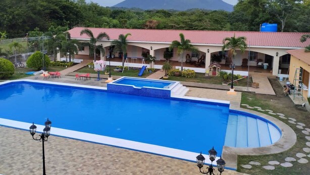 A hotel with a swimming pool, outdoor seating, and a view of a mountain. - Hotel Campestre Bella Vista (Moyagalpa)