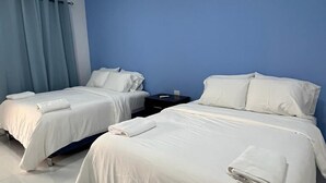 A hotel room with two beds, a nightstand, and a blue wall. - Hotel Campestre Bella Vista (Moyagalpa)