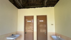 A restroom with two doors labeled "MALE" and "FEMALE," each with a sink and a trash bin.