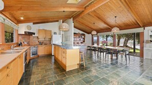 A spacious kitchen with wooden cabinets, a large island, and a dining area with bar stools. - Lake Eildon Retreat - Breathtaking Views - Sleeps 12 (Mansfield)