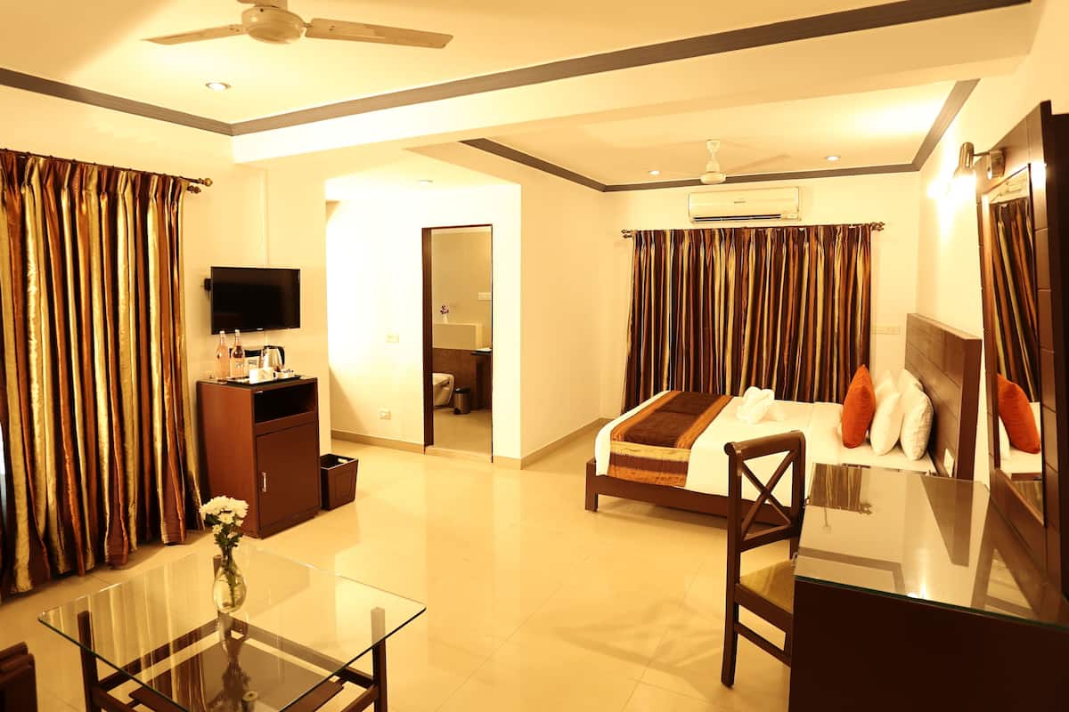 A hotel room with a bed, a TV, a desk, and a bathroom visible through an open door.