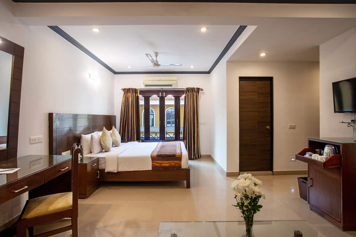 A hotel room with a bed, desk, chair, TV, and a window with curtains.
