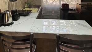 A kitchen with a marble countertop, two pendant lights, a window with a view of trees, and a toaster. - House Green (Ecatepec de Morelos)