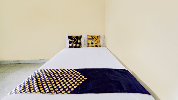 Ein Einzelbett mit zwei Kissen und einer gemusterten Decke.