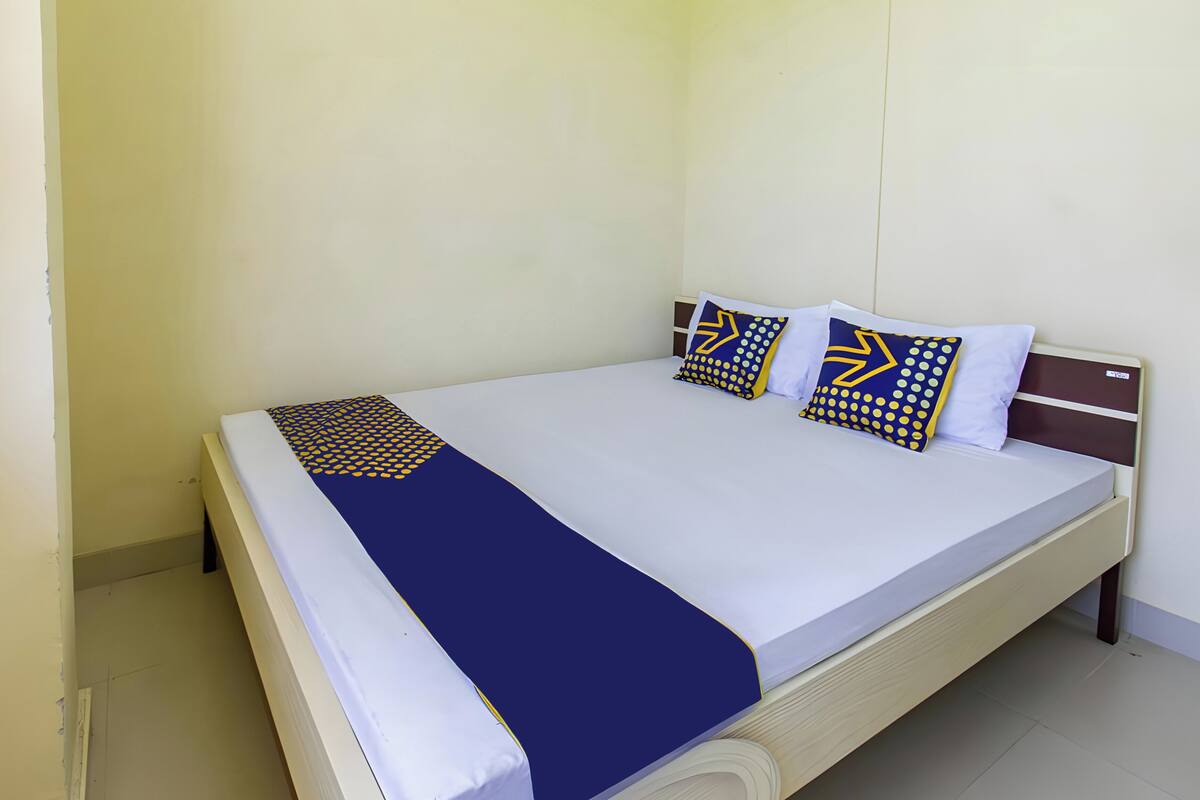 Een opgemaakt bed met een blauw-witte dekbedovertrek en twee decoratieve kussens.