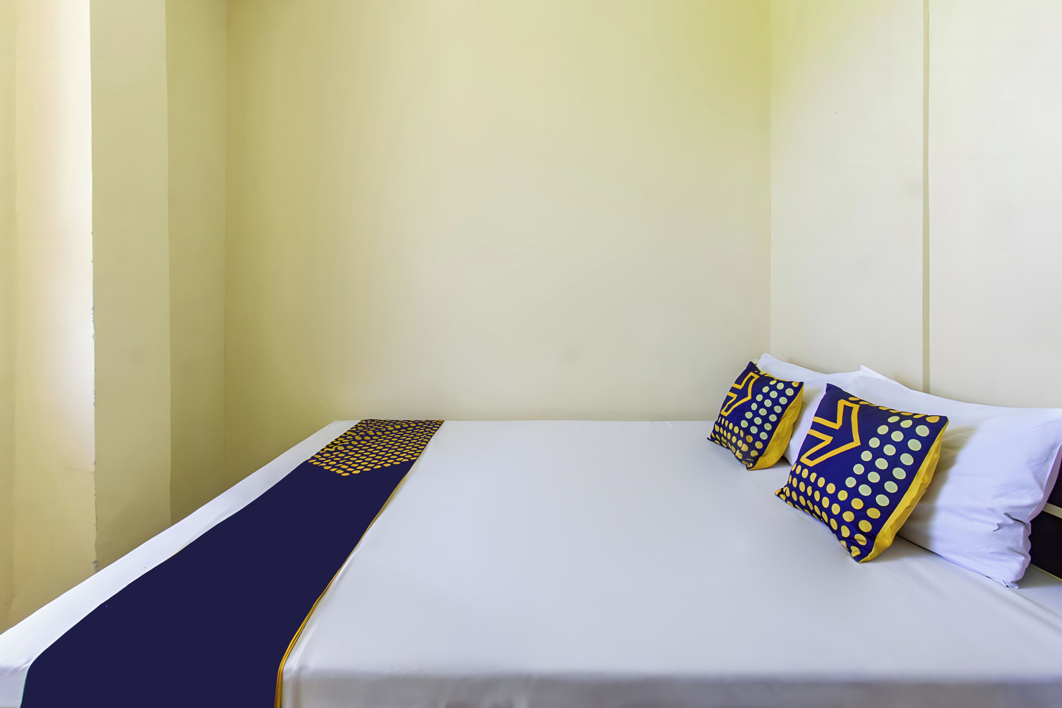 Una cama bien hecha con un colchón blanco, un corredor azul marino y tres almohadas de estampado geométrico.