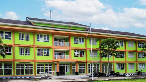 A multi-story building with a green and orange facade, large windows, and a flat roof. - OYO Life 93399 Kos Batulayar (Senggigi)