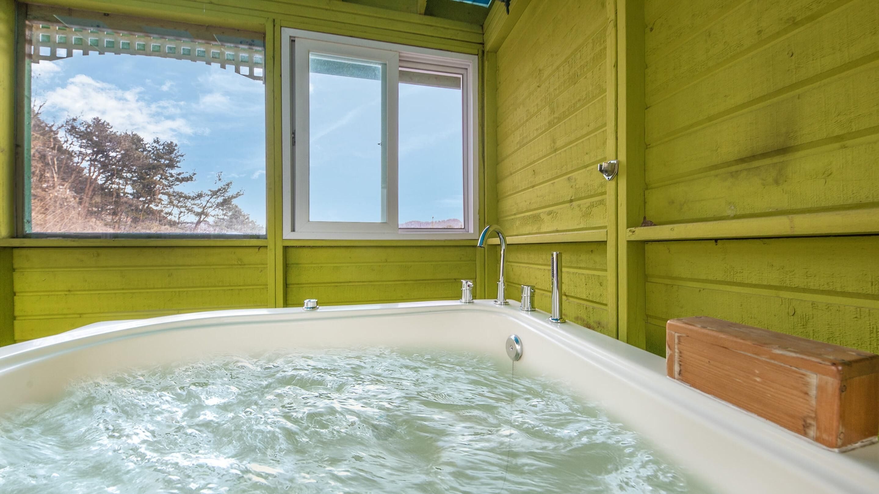Un jacuzzi en una habitación con paredes verdes y una ventana.