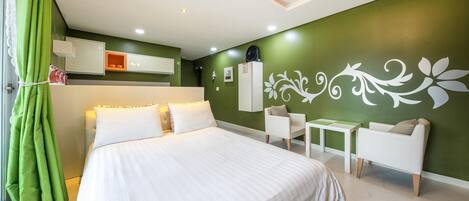 A modern bedroom with a large bed, a small table, two chairs, and a decorative wall design.