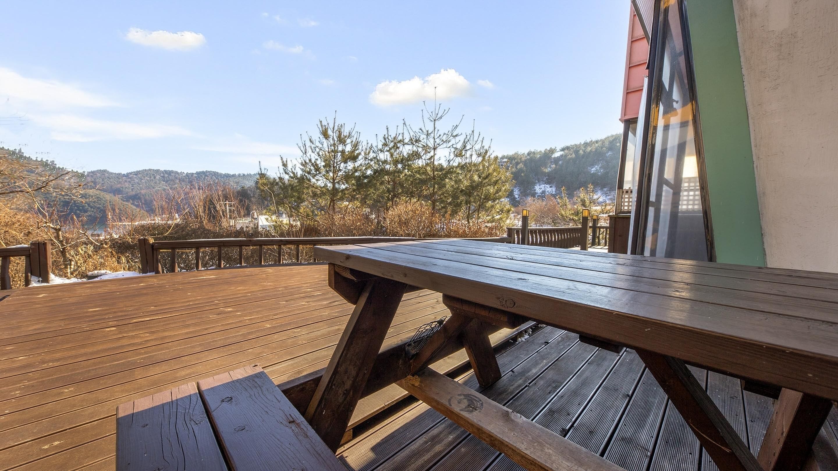 A wooden deck with a picnic table, overlooking a mountainous landscape.
