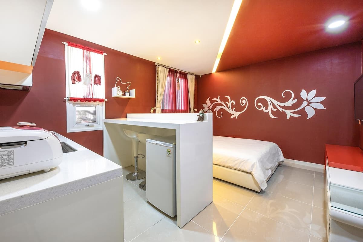 Une chambre d’hôtel compacte comprenant un coin cuisine, un lit et un petit bureau.
