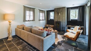A modern living room with a sofa, armchair, and fireplace. - Villa in Durbuy near Golf Course (Durbuy)