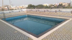 Una piscina en la azotea con solárium de baldosas y vista al paisaje urbano.