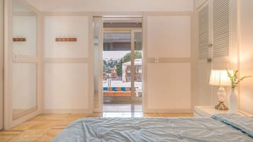 Un dormitorio con cama, una lámpara de noche y vistas a un área exterior con piscina y valla.
