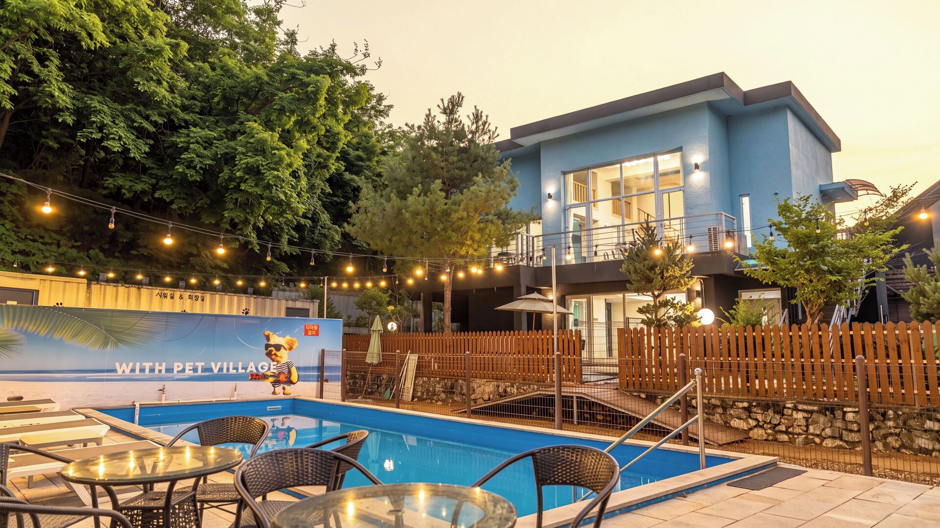 A pool area with lounge chairs and a sign reading 'WITH PET VILLAGE'.
