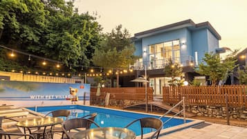 A pool area with lounge chairs and a sign reading 'WITH PET VILLAGE'.