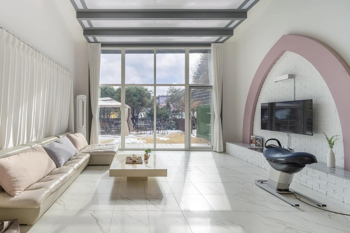 A modern living room with a sofa, coffee table, and a TV mounted on a brick wall.