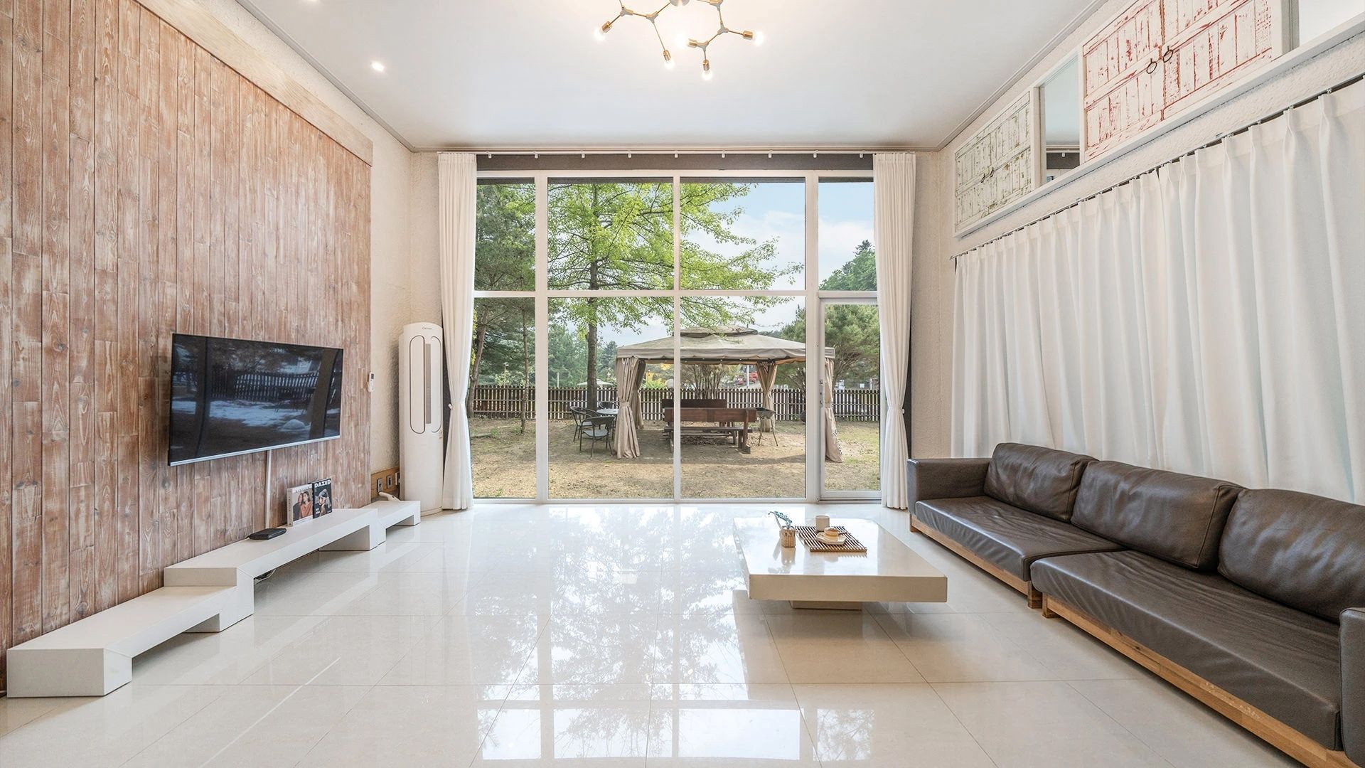 Una sala de estar moderna con un televisor de pantalla plana, un sofá, una mesa de centro y vistas a un patio exterior.