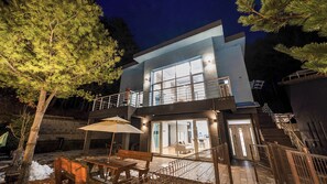 A modern two-story house with a balcony, a patio with a table and chairs, and a staircase leading to the upper level. - Hoengseong Withpet Village (Hoengseong)