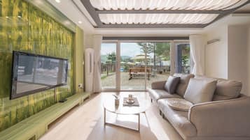Una sala moderna con un televisor de pantalla plana, un sofá de cuero, una mesa de centro de vidrio y vistas a un patio exterior.