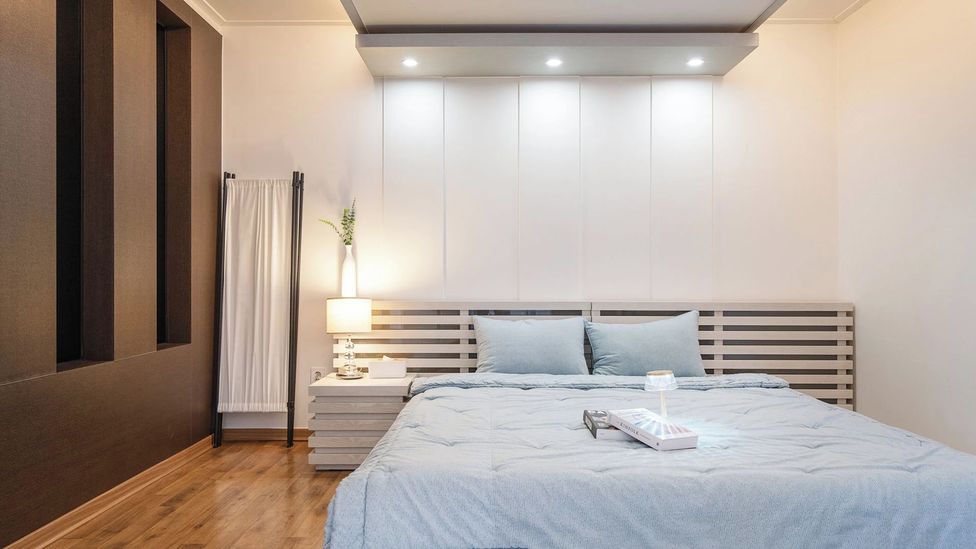 A modern bedroom with a bed, bedside tables, a lamp, and a window with curtains.