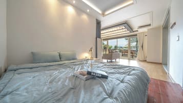 A modern bedroom with a large bed, a book, and a view of an outdoor patio area.
