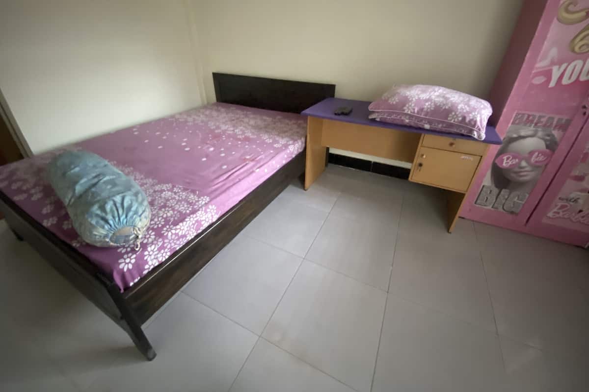 Une petite chambre avec un lit simple, un bureau et une armoire.