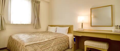 Una habitación de hotel con cama, escritorio, silla, lámpara y espejo.