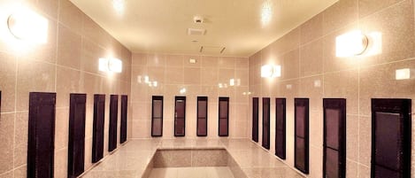 A long, narrow hallway with multiple doors and light fixtures on the walls.