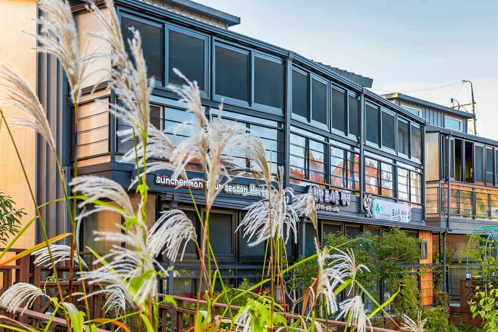 Een modern gebouw met grote ramen en een bordje met de tekst 'Sunchonman Season House'.