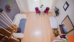 A compact living space with a sofa, two chairs, a small table, a TV, and a kitchen area. - Suncheonman 4Season Pension (Suncheon)