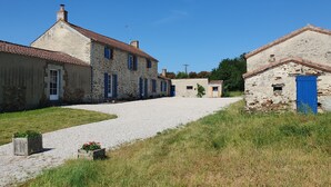 A rural stone building with a gravel driveway and a blue door.