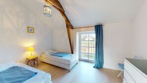 A bedroom with a bed, a desk, a lamp, and a window with curtains.