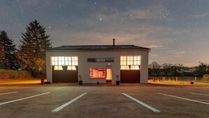 A building with two garage doors, a sign reading "IGOL," and a parking lot with marked spaces. - Vintage Loft Garage Proche du Parc Le Pal (Saint-Agnan)