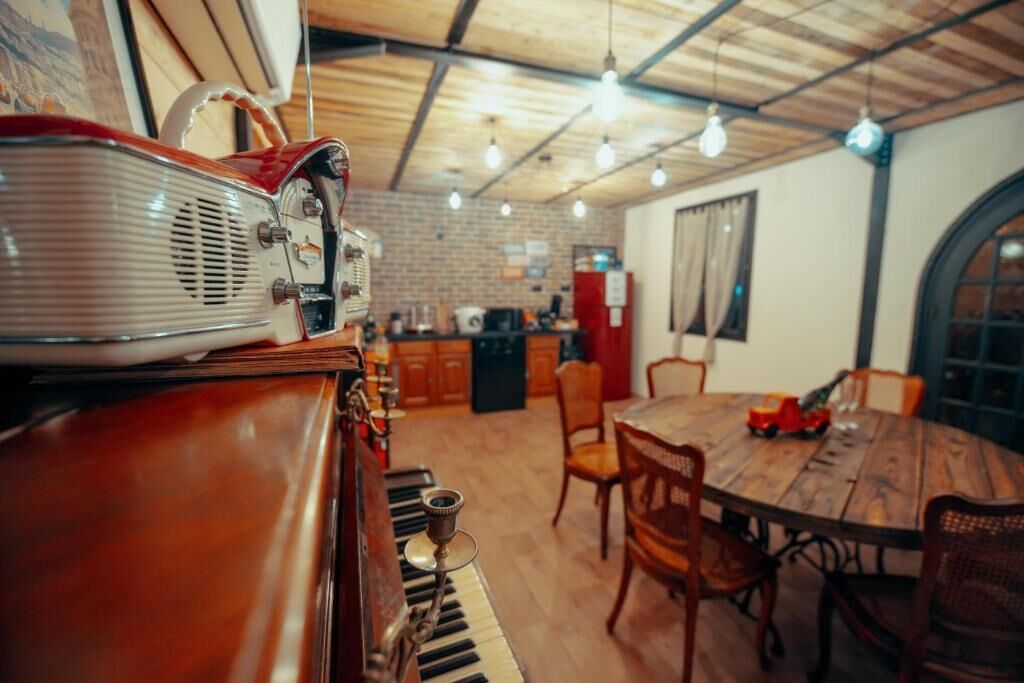 Un coin repas chaleureux avec une table et des chaises en bois, une radio d’époque et un piano.