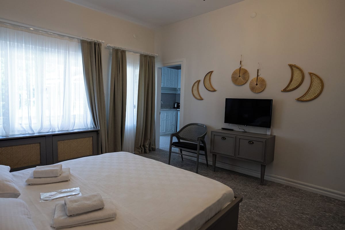 Quarto de hotel com uma cama grande, televisão e escrivaninha.