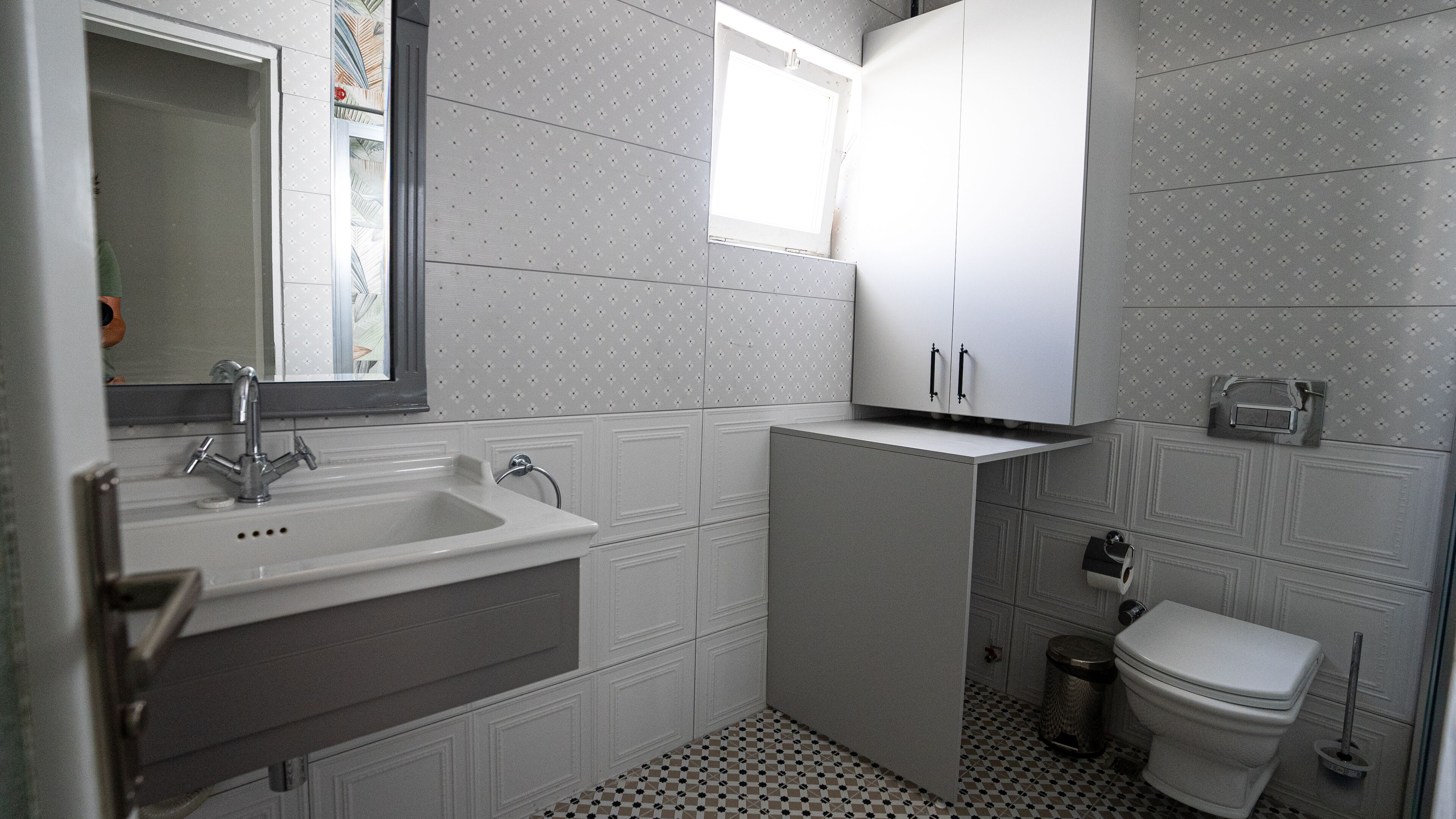 Une salle de bain équipée d’un lavabo, d’un miroir, d’un meuble de rangement, de toilettes et d’une fenêtre.