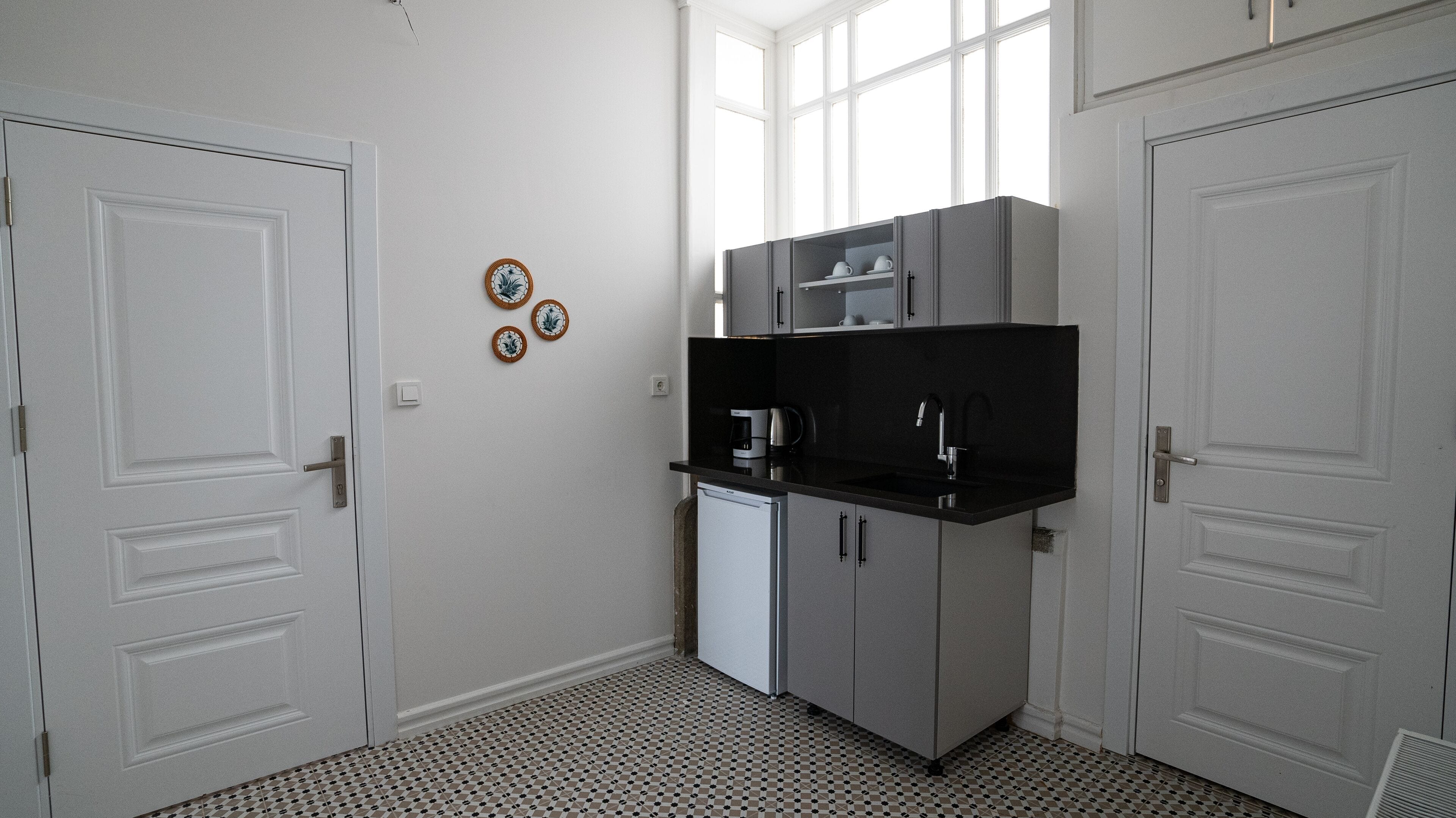 A compact kitchen with a built-in dishwasher, a black countertop, and a window above the sink.