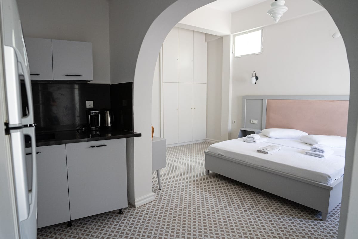 Quarto de hotel compacto com cozinha compacta, uma cama e um banheiro pequeno.
