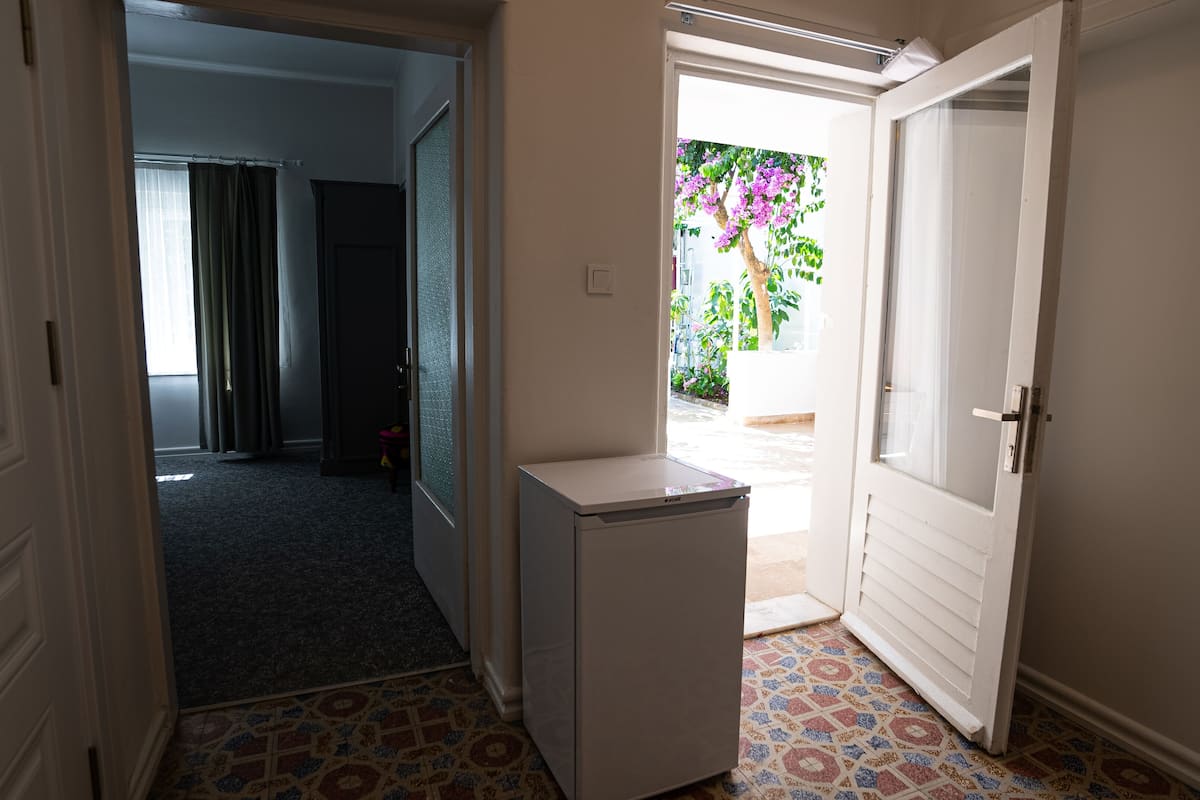Corredor com frigorífico, porta para o exterior e soalho estampado.