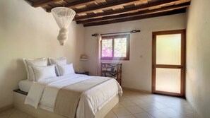 A bedroom with a bed, a window with curtains, a door, and a ceiling fan.