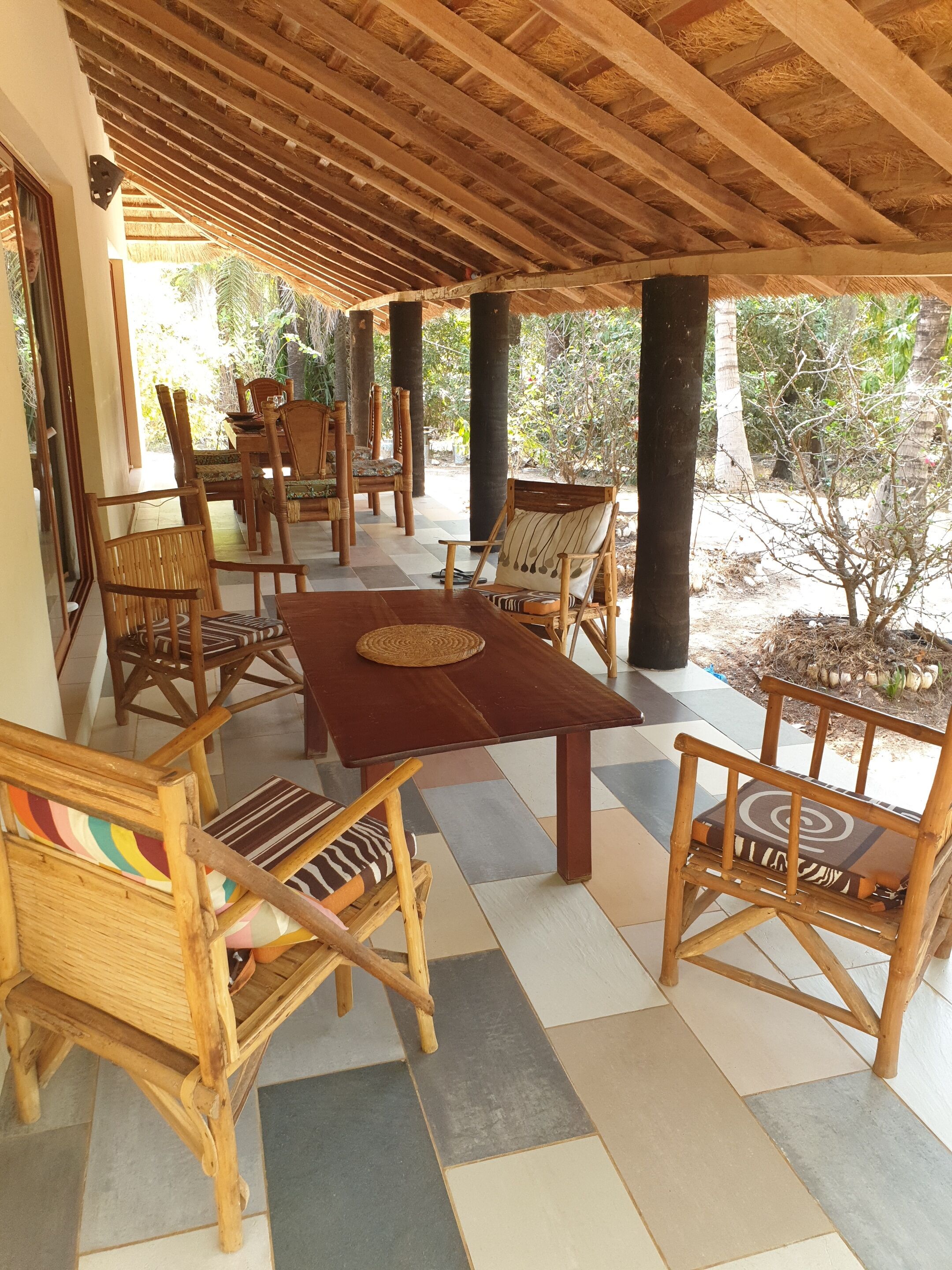 An outdoor patio with wooden furniture and a thatched roof.