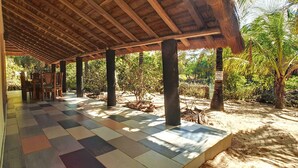 Un espace extérieur abrité, doté d’un sol carrelé et de piliers en bois.