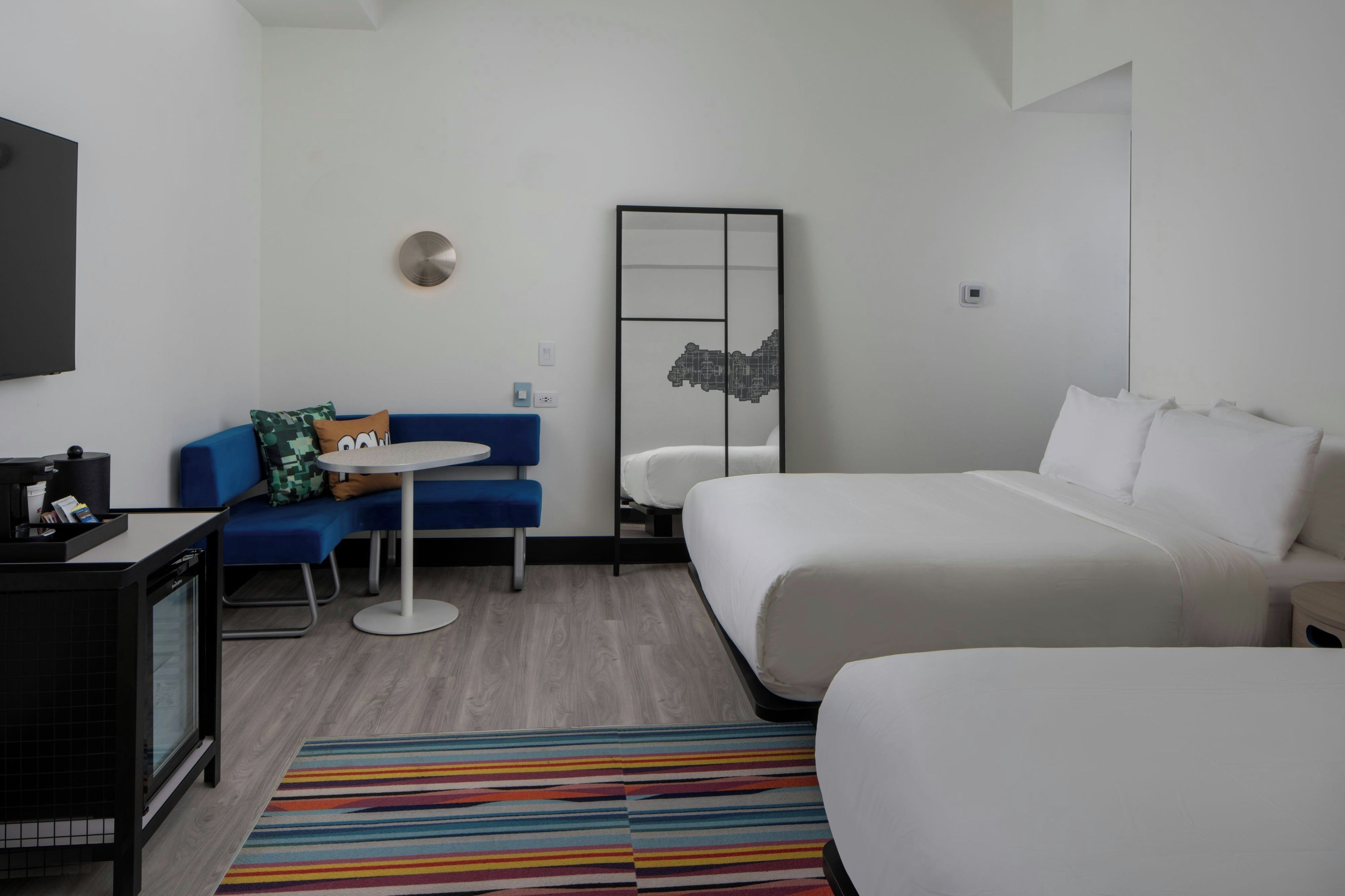A hotel room with a bed, a sofa, a small table, and a TV.