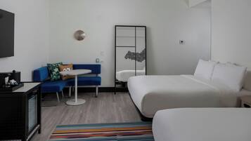 A hotel room with a bed, a sofa, a small table, and a TV.