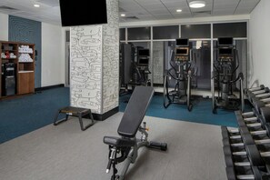 Ett gym med träningsutrustning, en bänk och en vattenautomat.